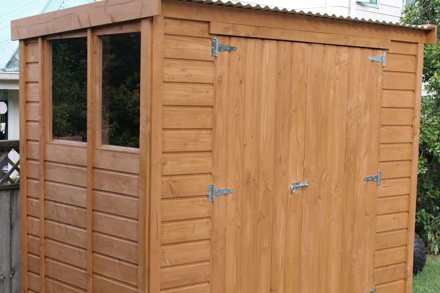 A small timber garden shed made for wood. Displayed as storage for garden tools